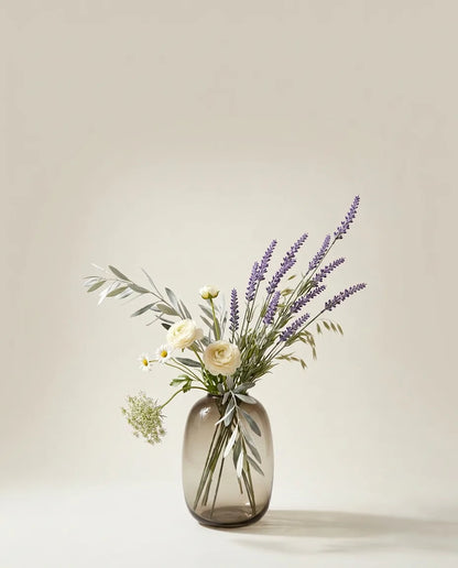 Bouquet artificiel de lavande, renoncules et marguerites violet et blanc dans un vase en verre ambré
