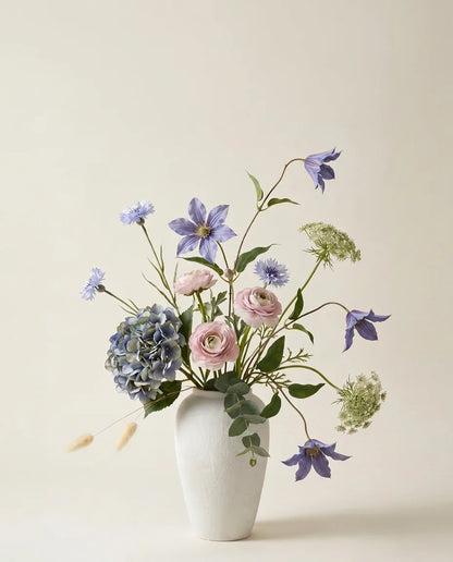 Bouquet artificiel d'hortensias, clématites et renoncules bleu et rose dans un vase en céramique