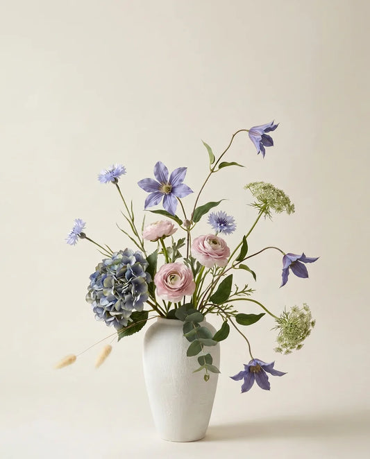 Bouquet artificiel d'hortensias, clématites et renoncules bleu et rose dans un vase en céramique