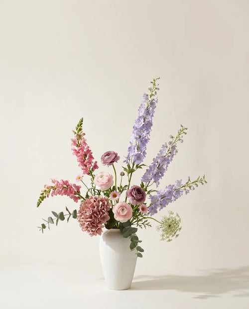 Bouquet artificiel d'hortensias, delphiniums et renoncules violet et rose dans un vase en céramique