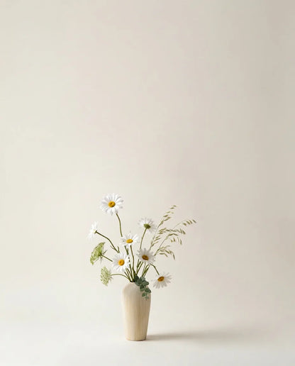 Bouquet artificiel de marguerites, blé et ammi blanc et jaune dans un vase en céramique