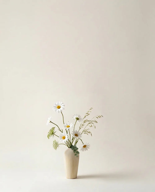 Bouquet artificiel de marguerites, blé et ammi blanc et jaune dans un vase en céramique