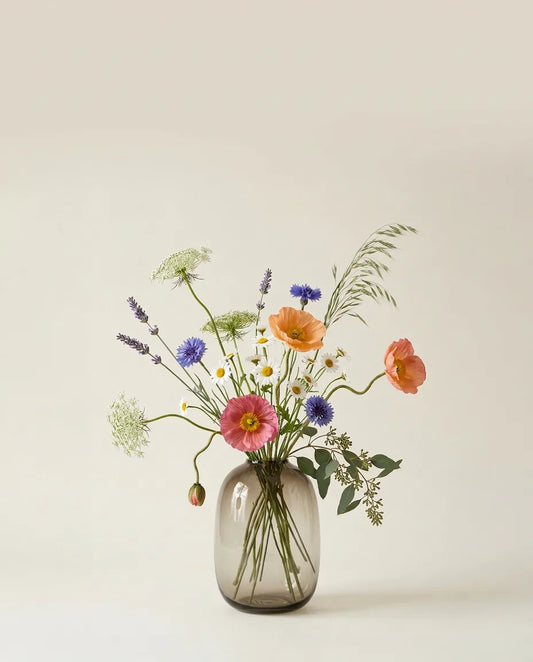 Bouquet artificiel de pavots d'Islande et marguerites orange et blanc dans un vase en verre ambré