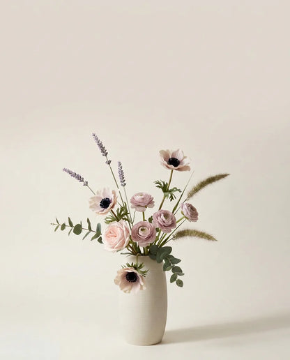 Bouquet artificiel de roses, anémones et renoncules rose et violet dans un vase en céramique