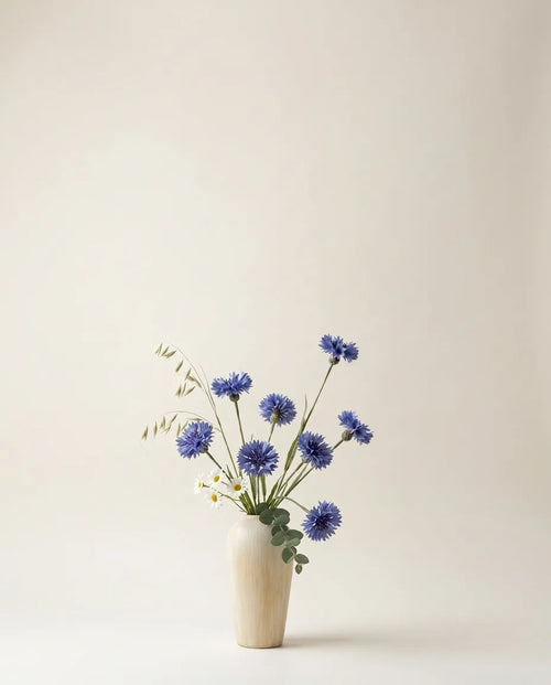 Bouquet artificiel de scabiosa et marguerites blanc et bleu dans un vase en céramique