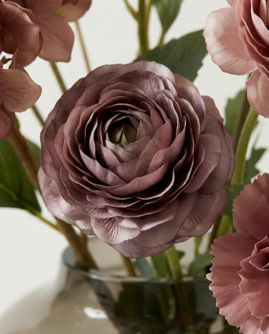 Gros plan sur les renoncules artificielles du bouquet Bordeaux Profond