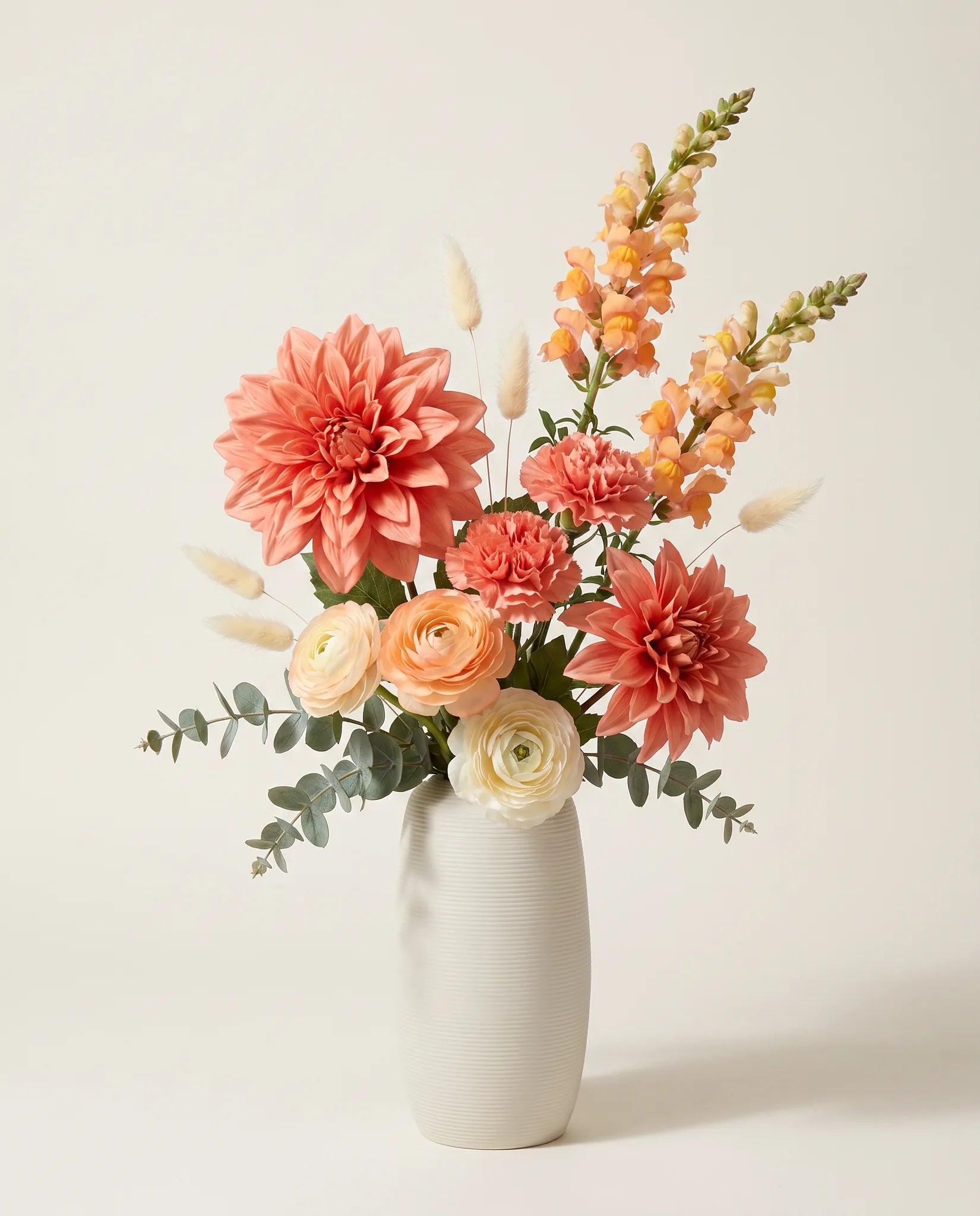 Bouquet artificiel de dahlias, renoncules et œillets orange et rose en gros plan