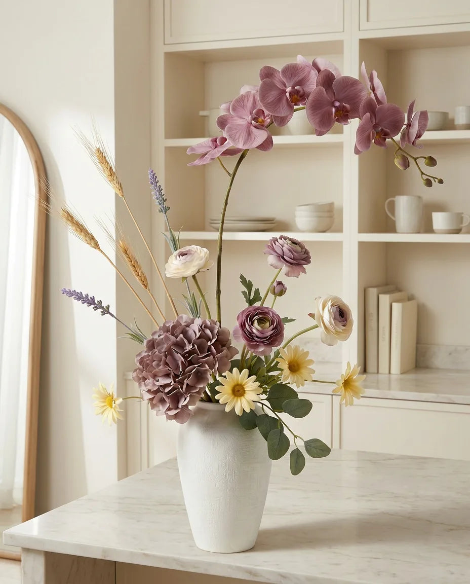Bouquet artificiel violet et jaune sur un îlot en marbre clair dans une cuisine crème