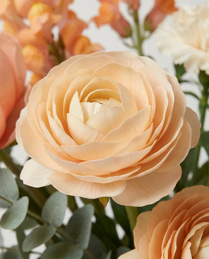Gros plan sur les renoncules artificielles du bouquet Pêche Melba