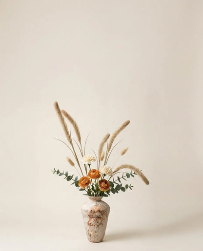 Bouquet artificiel de renoncules, œillets et pennisetum beige dans un vase en céramique
