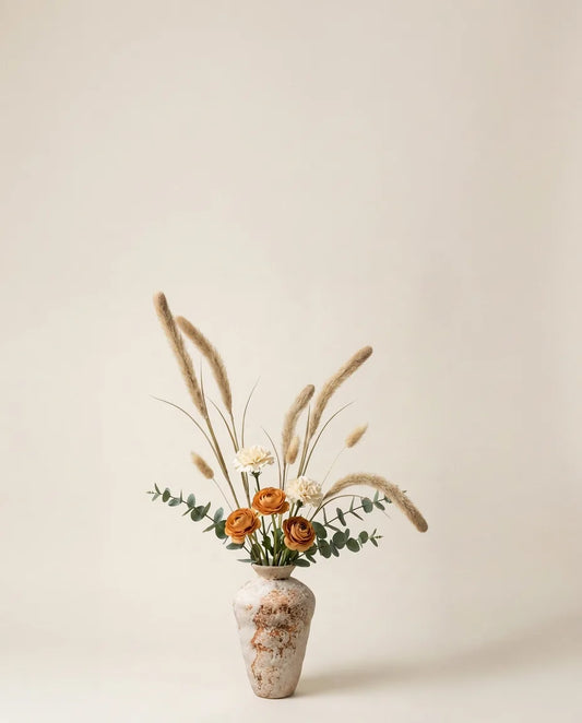 Bouquet artificiel de renoncules, œillets et pennisetum beige dans un vase en céramique