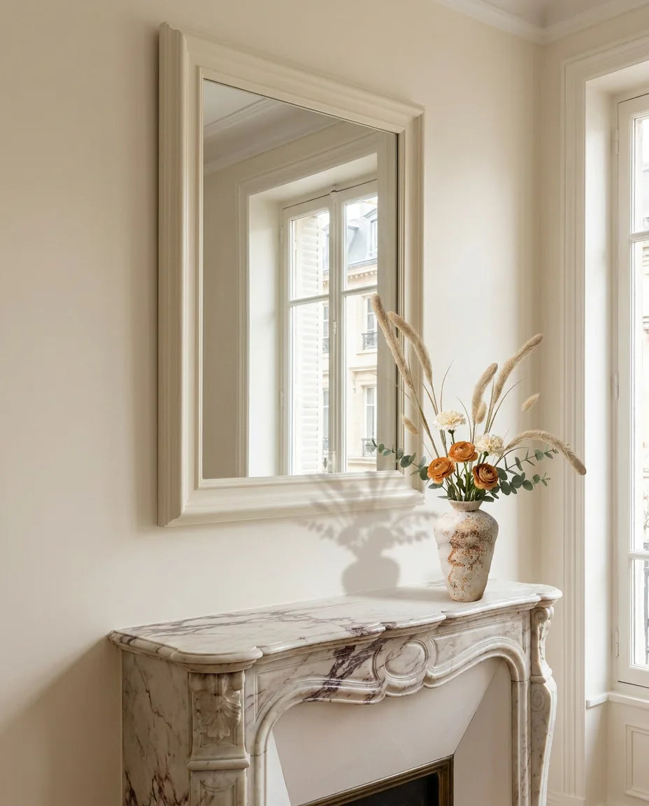 Bouquet artificiel beige sur une cheminée en marbre devant un grand miroir, salon parisien