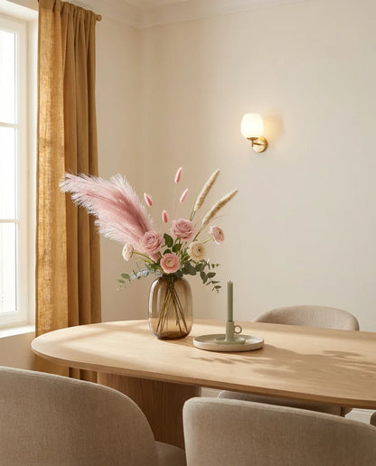 Bouquet artificiel rose et beige sur une table ovale en chêne clair dans une salle à manger, applique laiton