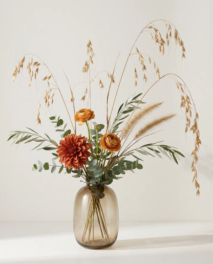 Bouquet artificiel de dahlias, renoncules et blé orange et beige en gros plan