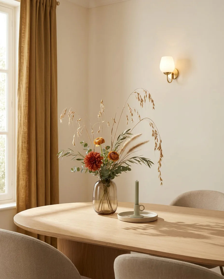 Bouquet artificiel orange et beige sur une table ovale en chêne clair dans une salle à manger