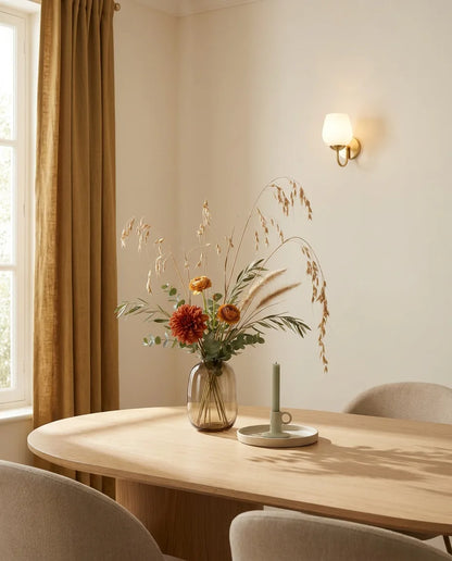 Bouquet artificiel orange et beige sur une table ovale en chêne clair dans une salle à manger