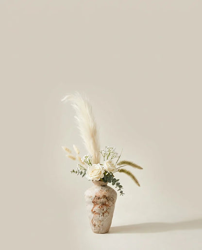 Bouquet artificiel de roses, pennisetum et eucalyptus blanc et beige dans un vase en céramique