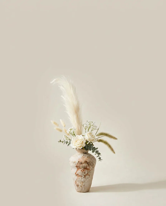 Bouquet artificiel de roses, pennisetum et eucalyptus blanc et beige dans un vase en céramique