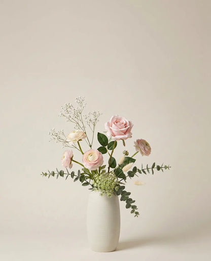 Bouquet artificiel de roses, renoncules et lagurus rose et blanc dans un vase en céramique