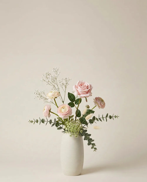 Bouquet artificiel de roses, renoncules et lagurus rose et blanc dans un vase en céramique