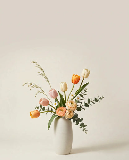 Bouquet artificiel de tulipes, renoncules et marguerites orange et rose dans un vase en céramique
