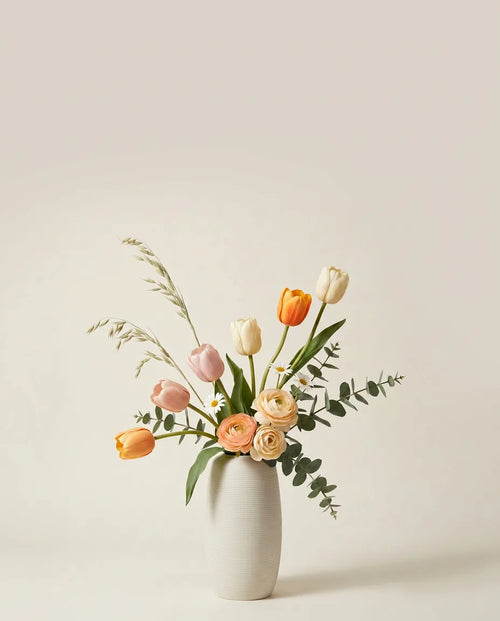 Bouquet artificiel de tulipes, renoncules et marguerites orange et rose dans un vase en céramique