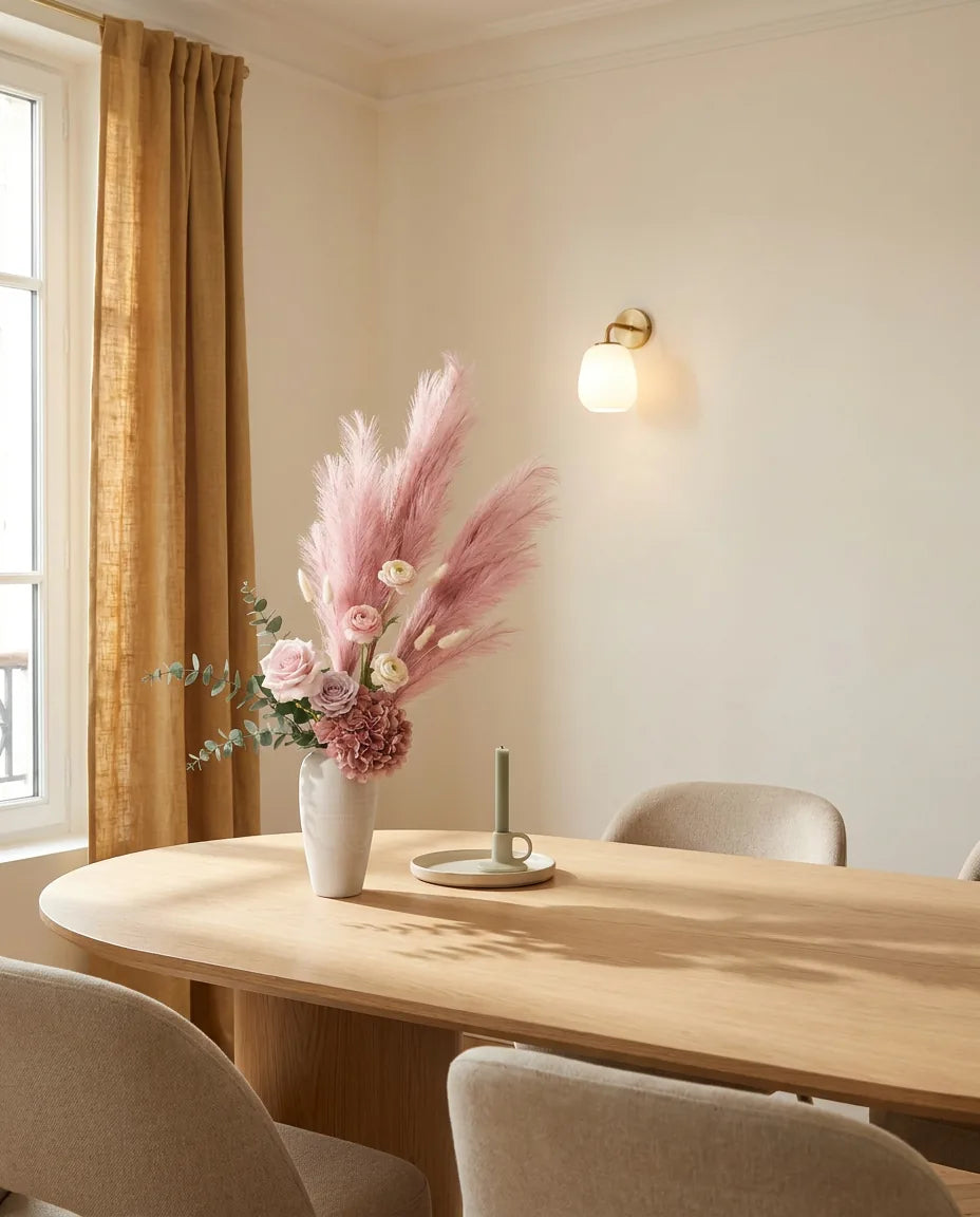 Bouquet artificiel rose et beige sur une table ovale en chêne clair dans une salle à manger