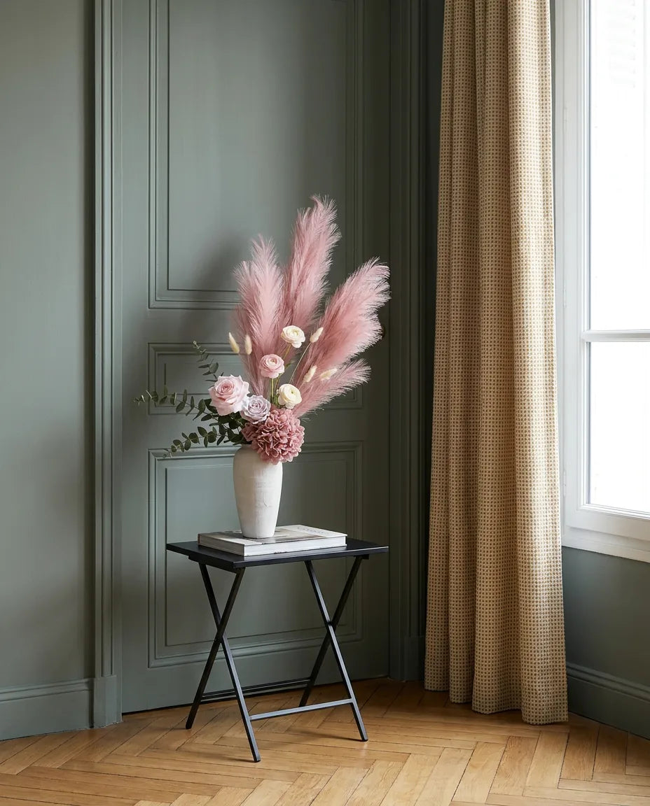 Bouquet artificiel rose et beige sur une table d'appoint noire près d'une porte vert sauge