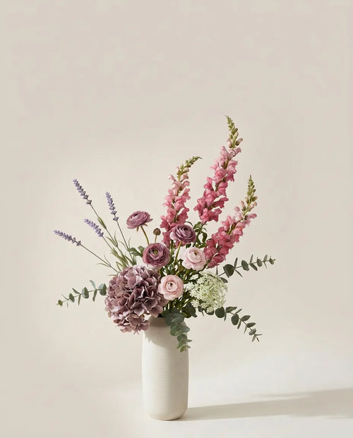 Bouquet artificiel d'hortensias, mufliers et renoncules rose et violet dans un vase en céramique