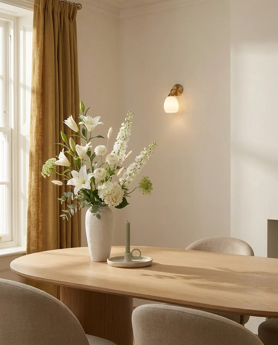 Bouquet artificiel blanc et vert sur une table ovale en chêne clair dans une salle à manger