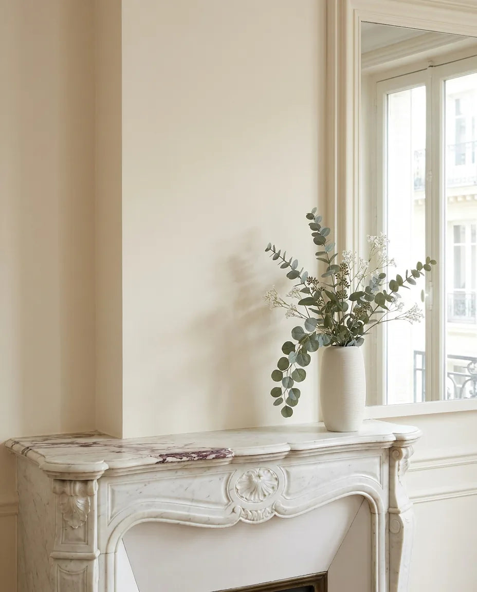 Bouquet artificiel vert et blanc sur une cheminée en marbre dans un salon parisien