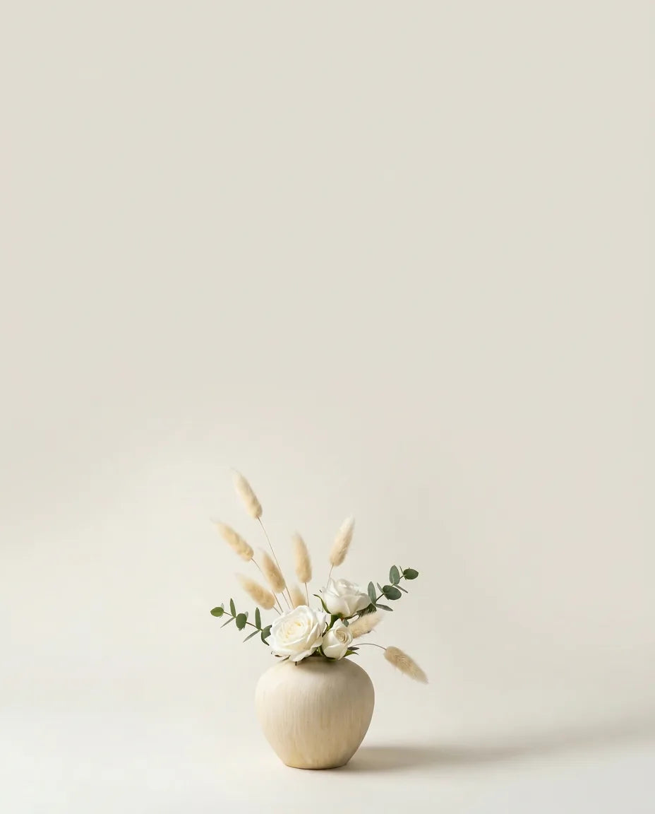 Bouquet artificiel de roses, lagurus et eucalyptus blanc et vert dans un vase en céramique