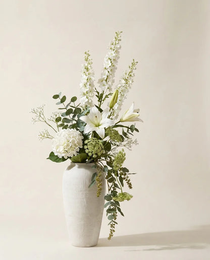 Bouquet artificiel de lys, hortensias et delphinium blanc et vert dans un vase en céramique