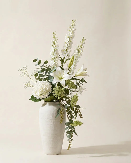 Bouquet artificiel de lys, hortensias et delphinium blanc et vert dans un vase en céramique