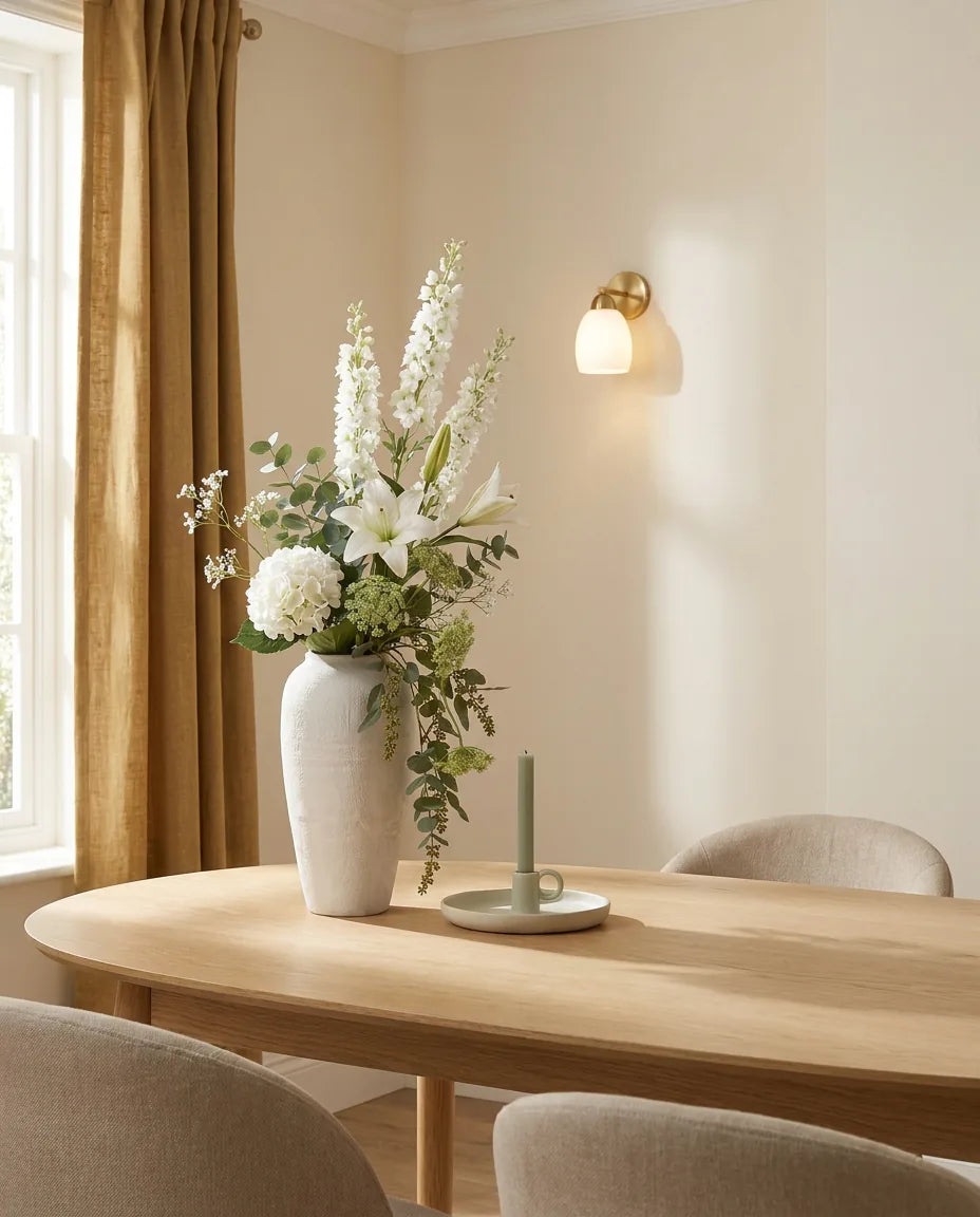 Bouquet artificiel blanc et vert sur une table ovale en chêne clair dans une salle à manger
