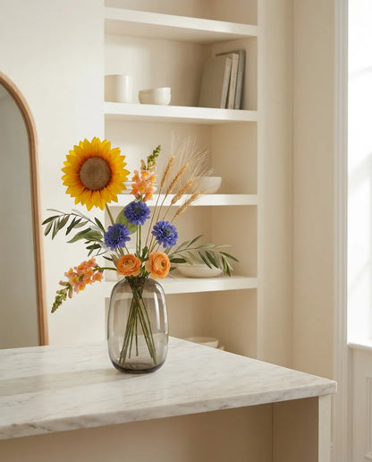 Bouquet artificiel jaune et bleu sur un îlot en marbre clair dans une cuisine crème