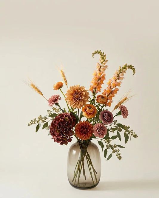 Bouquet artificiel de dahlias, hortensias et renoncules orange et beige dans un vase en verre ambré