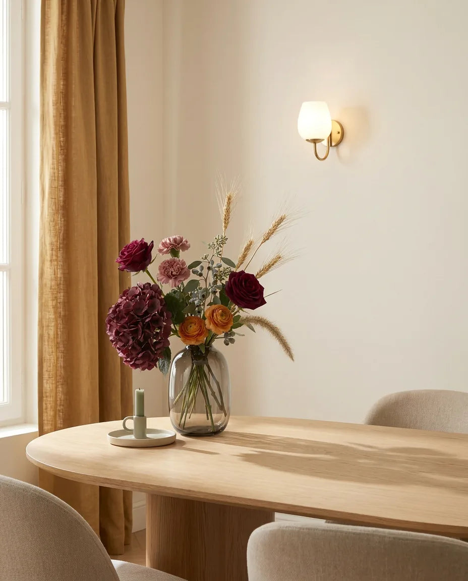 Bouquet artificiel rouge et rose sur une table ovale en chêne clair dans une salle à manger