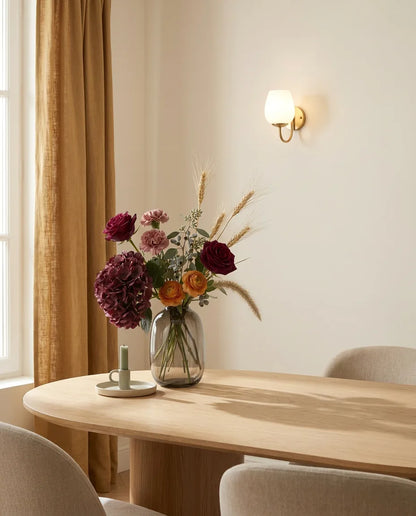 Bouquet artificiel rouge et rose sur une table ovale en chêne clair dans une salle à manger