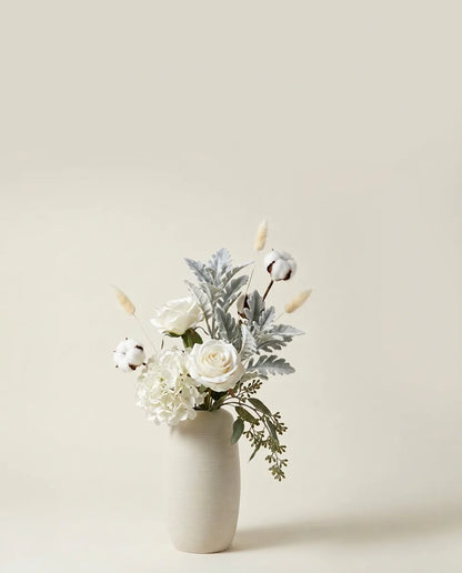 Bouquet artificiel de roses, hortensias et cinéraire blanc et vert dans un vase en céramique
