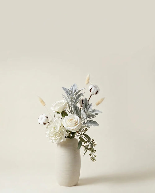 Bouquet artificiel de roses, hortensias et cinéraire blanc et vert dans un vase en céramique