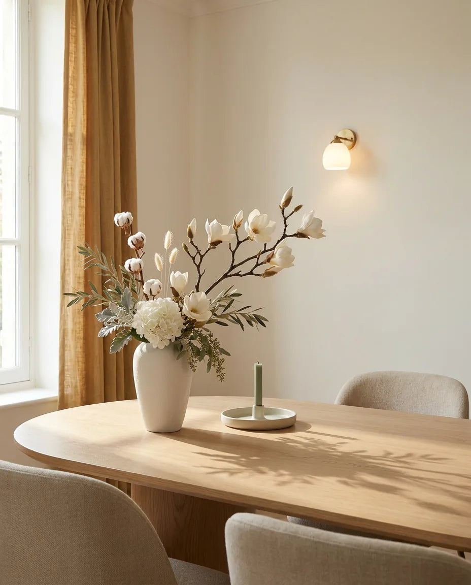 Bouquet artificiel blanc et beige sur une table ovale en chêne clair dans une salle à manger