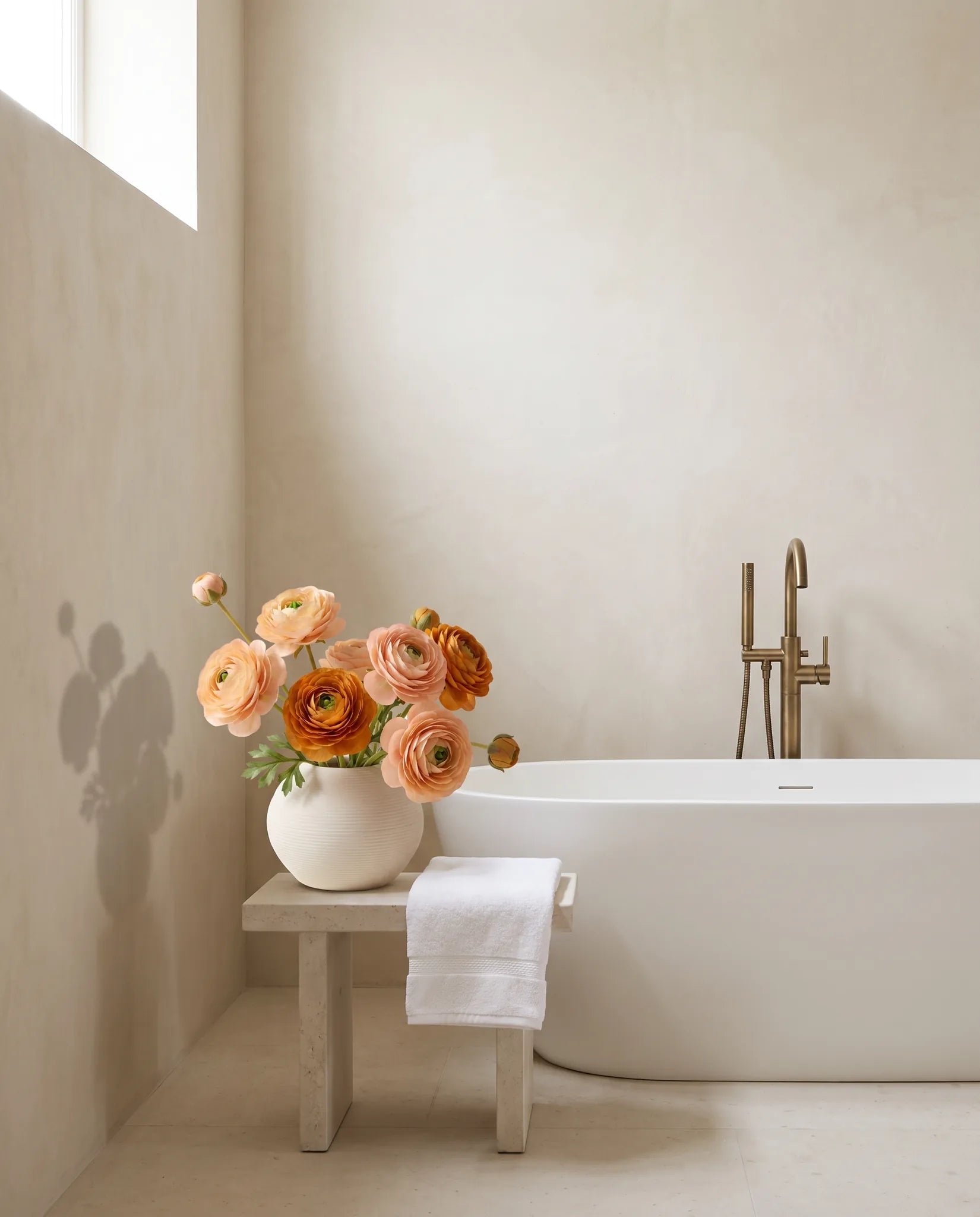 Bouquet artificiel rose abricot dans une salle de bain, près d'une baignoire îlot