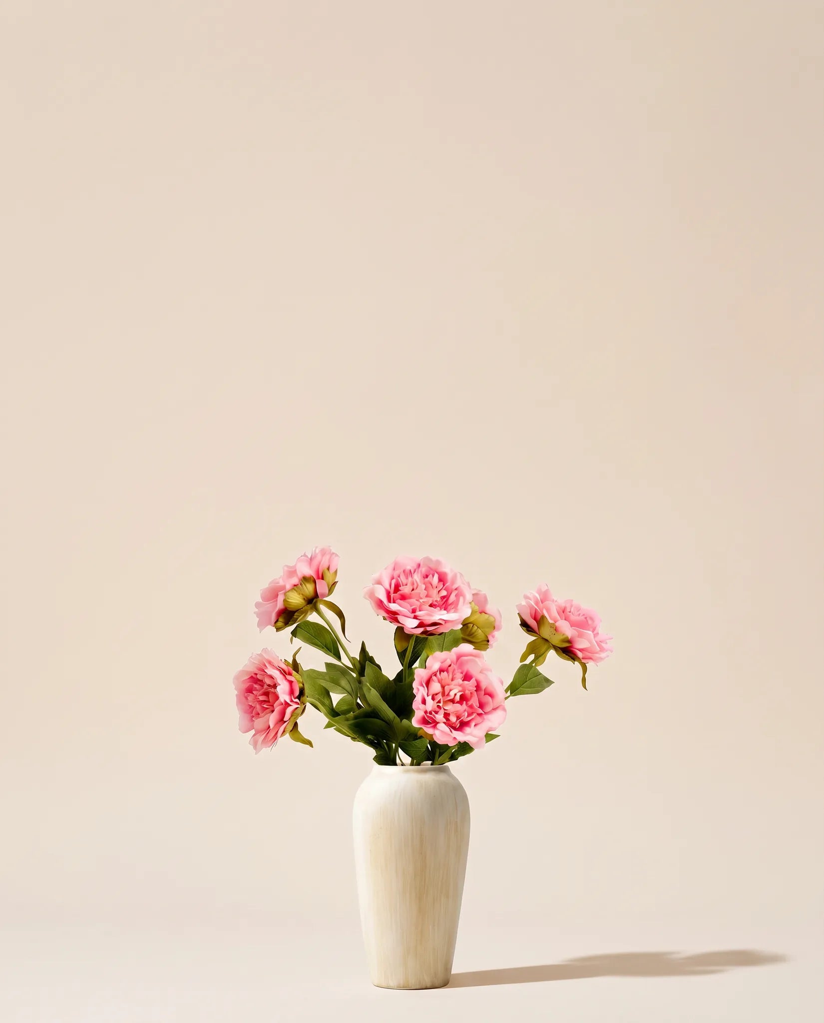 Bouquet artificiel de pivoines rose tendre dans un vase en céramique