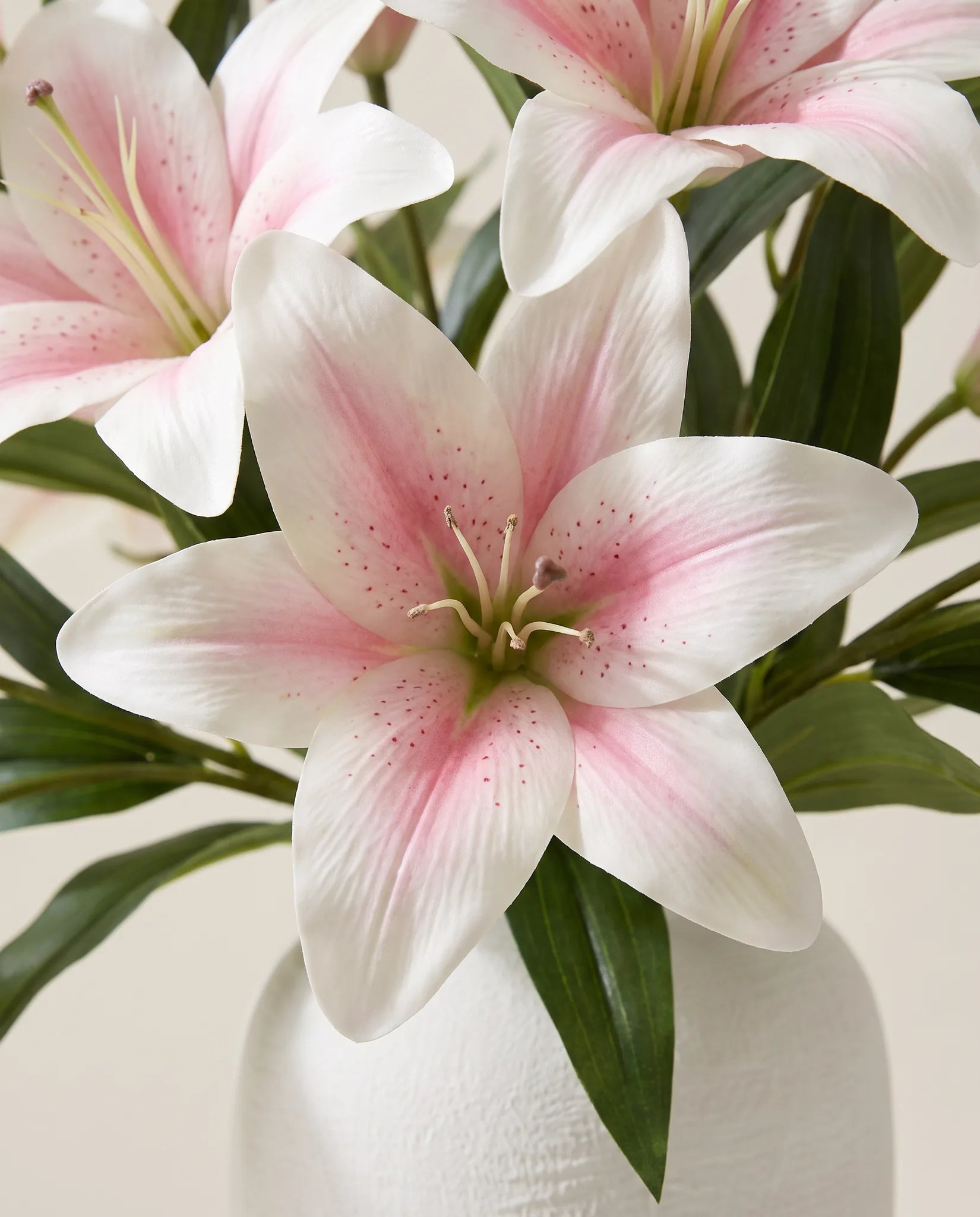 Gros plan sur les lys artificiels du bouquet Aube Rosée