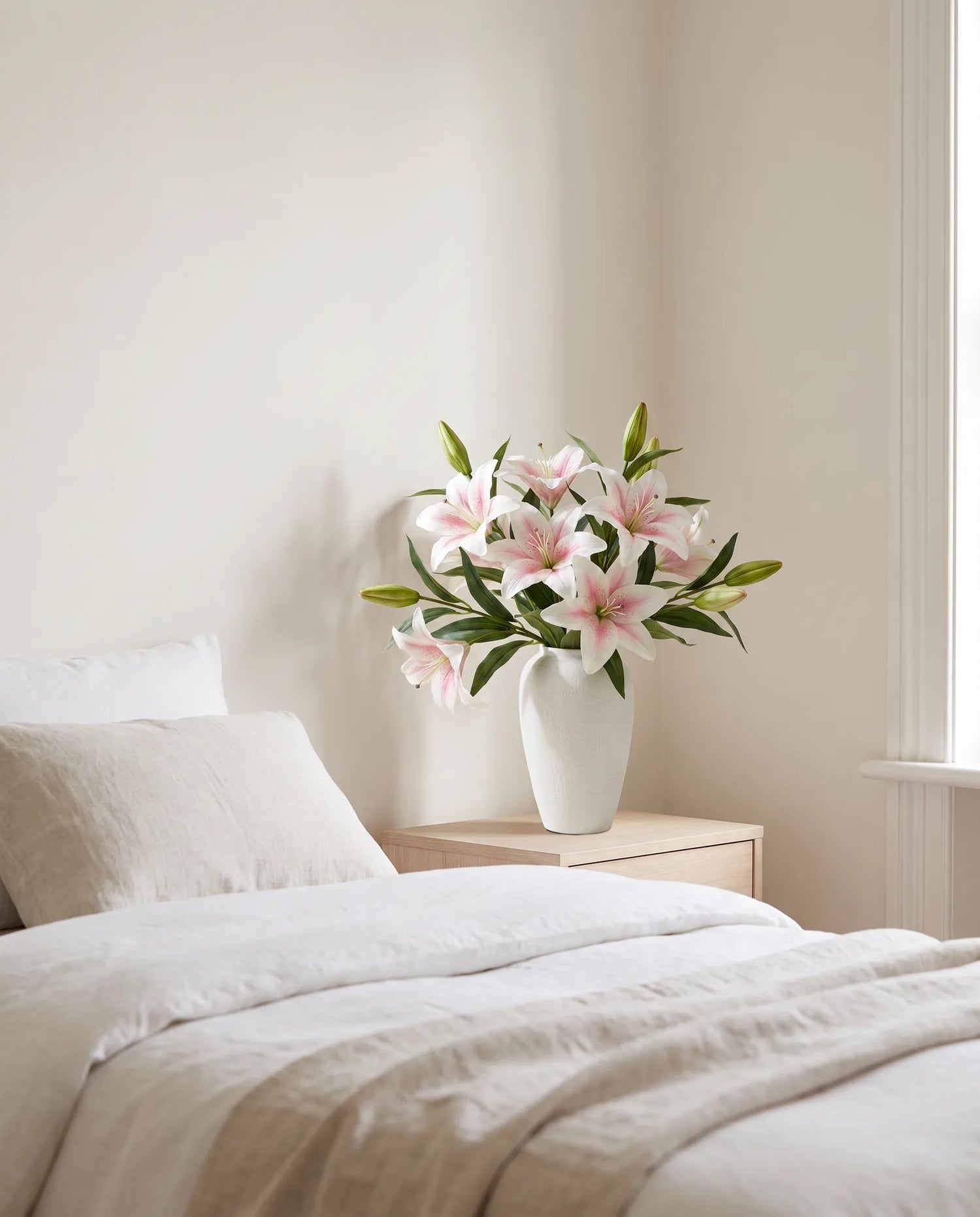 Bouquet artificiel blanc posé sur une table de chevet, lumière du matin dans la chambre