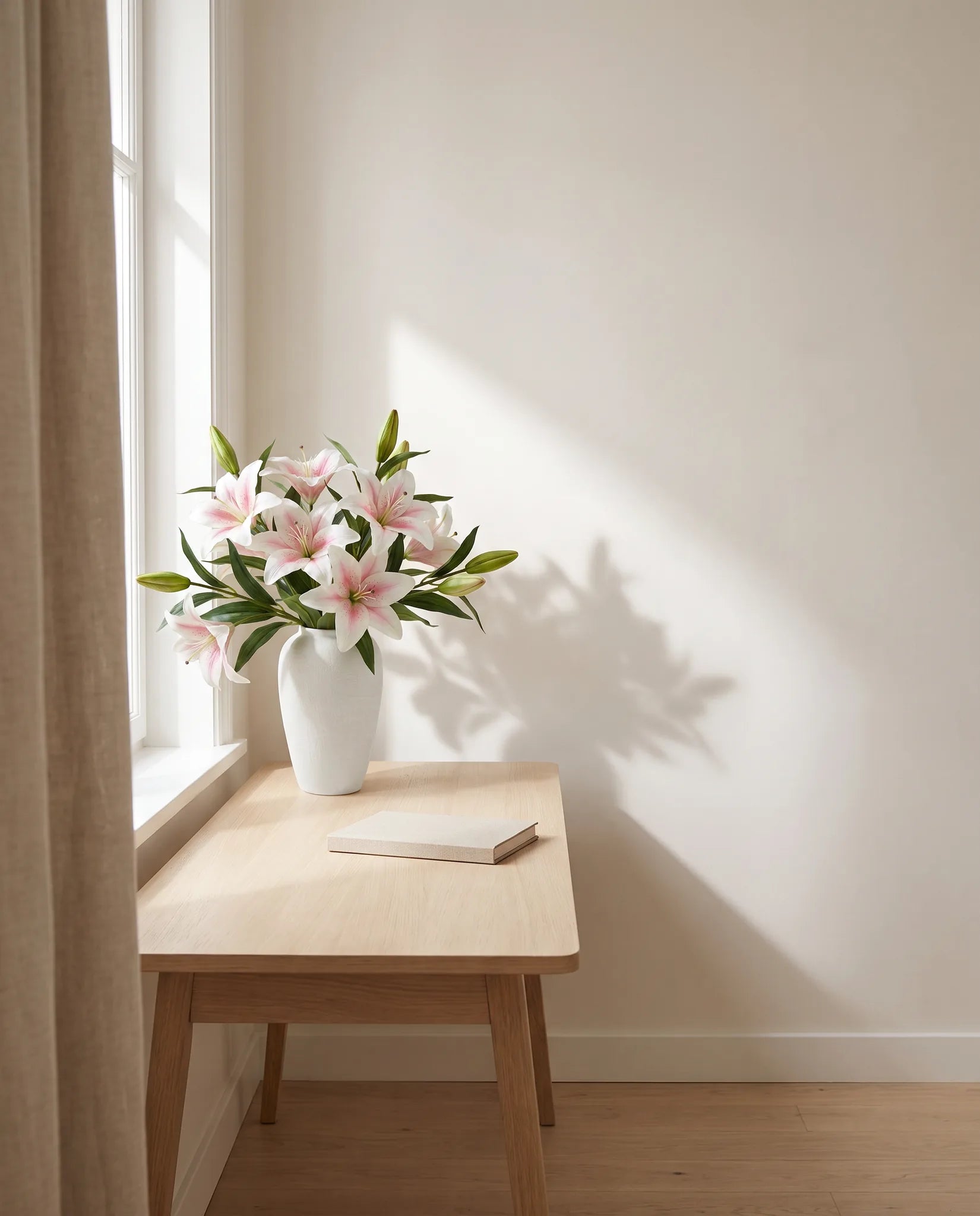Bouquet artificiel blanc sur une table en chêne clair, bureau baigné de lumière latérale
