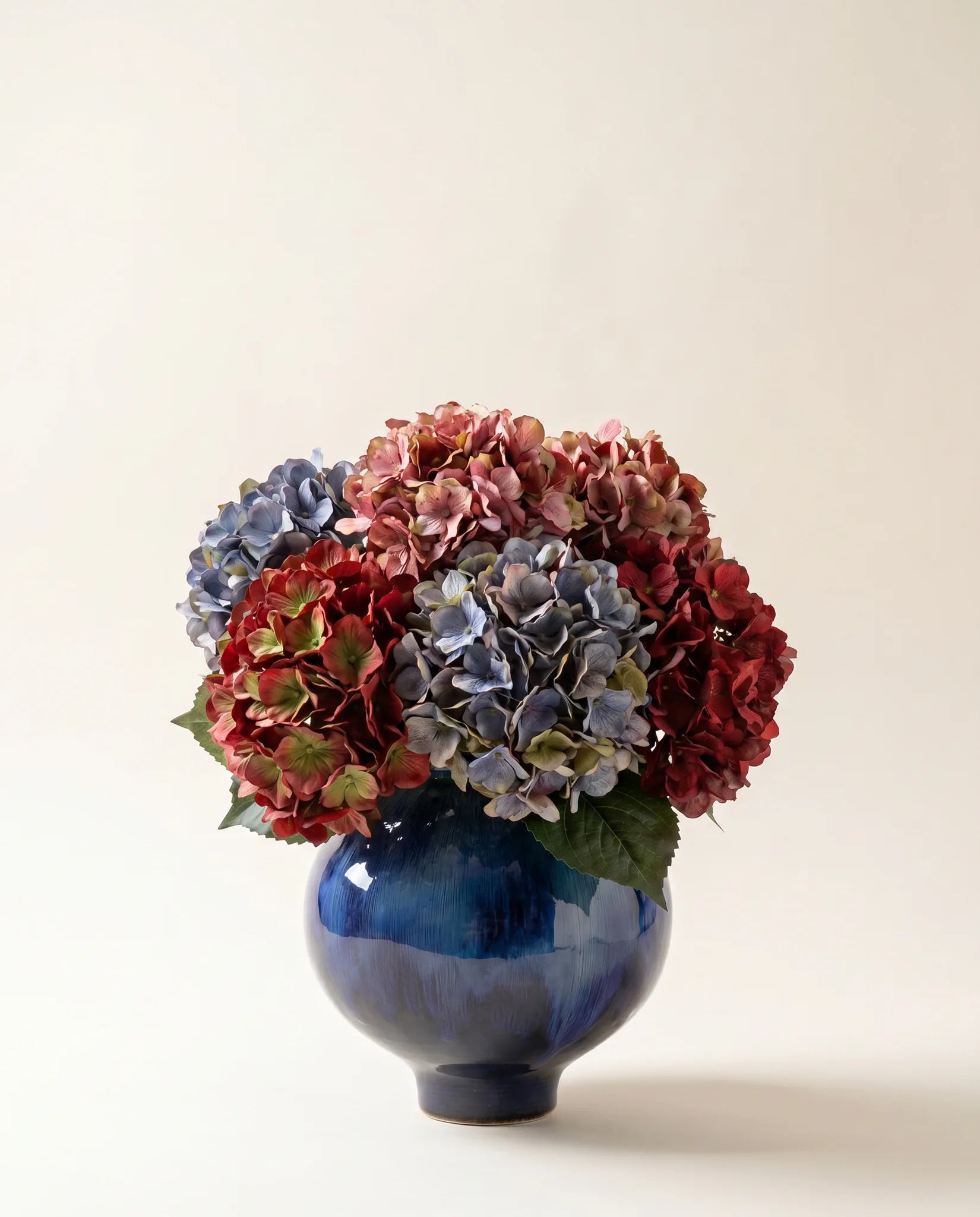Vase céramique émaillé bleu nuit avec bouquet d'hortensias multicolores artificiels