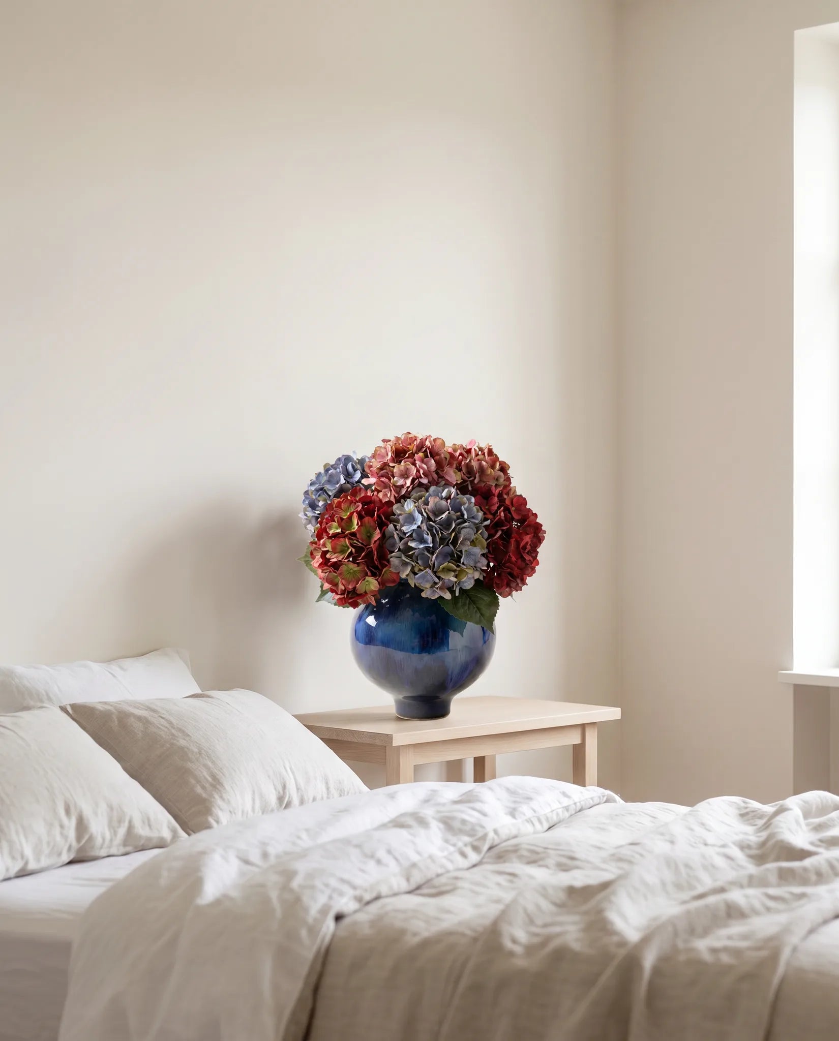 Grand bouquet artificiel aux teintes vintage dans une chambre au linge de lit en lin