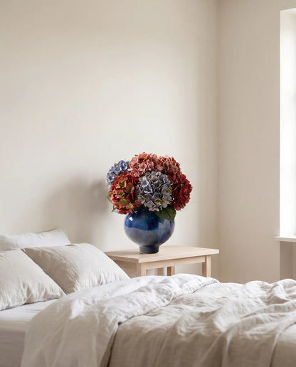 Grand bouquet artificiel aux teintes vintage dans une chambre au linge de lit en lin